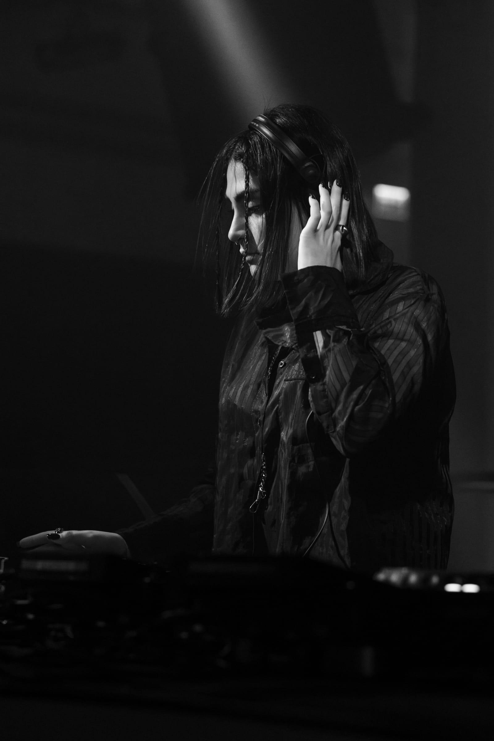 Black-and-white photo of 5OGOL holding headphones to one ear in the booth