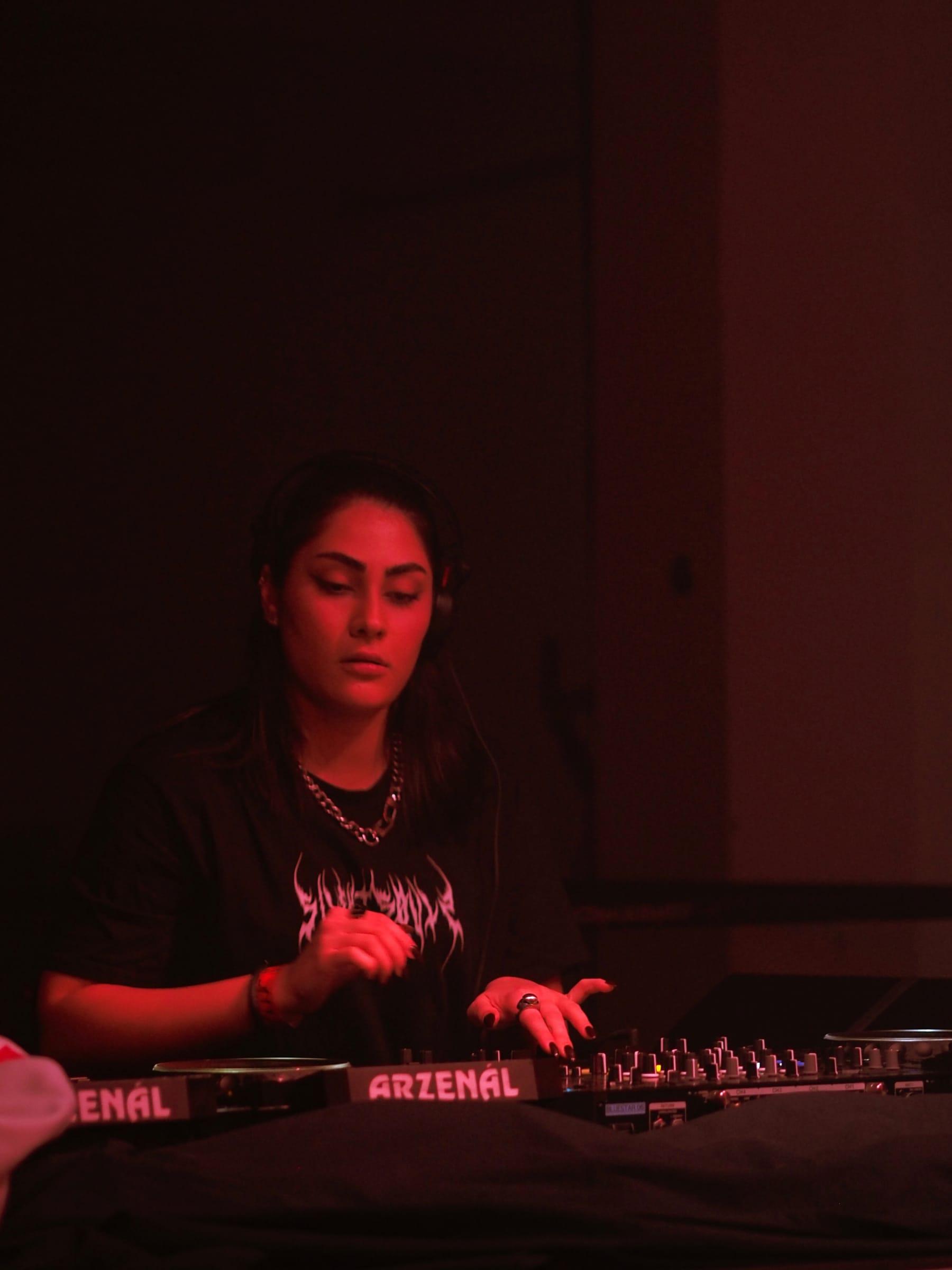 5OGOL at the mixer under red booth light, eyes down on the decks