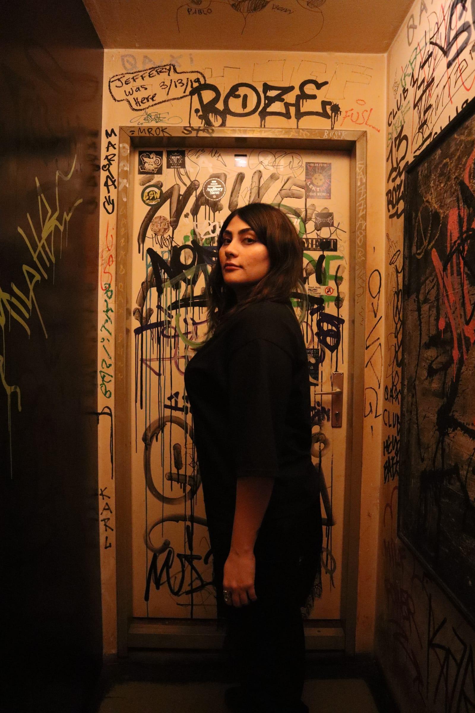 5OGOL standing in a graffiti-covered doorway